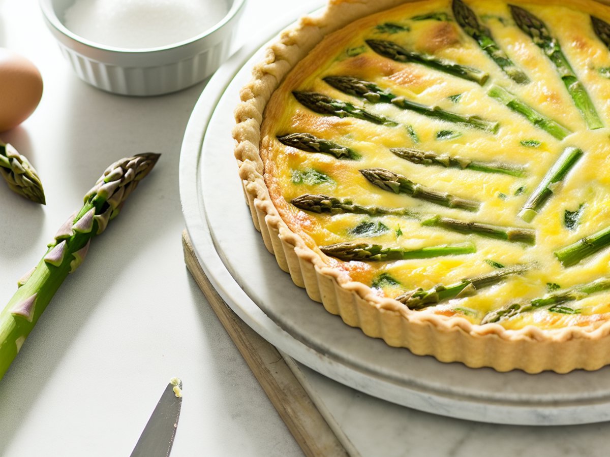 Ganze Spargel-Zitronen-Quiche mit Gruyère in runder Backform auf rustikalem Holztisch, professionelle Food-Fotografie